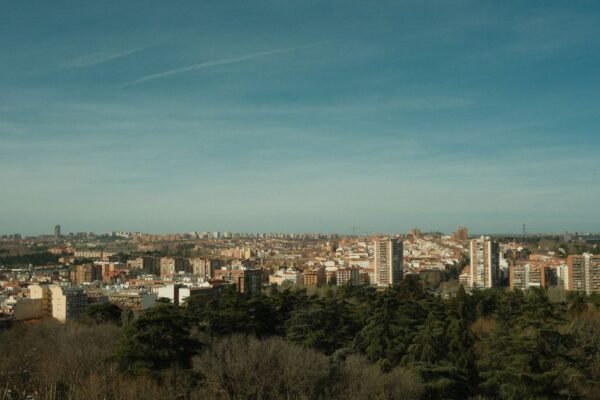 Una amplia vista del horizonte de Madrid bajo un cielo azul claro, rodeado de arquitectura urbana y vegetación.