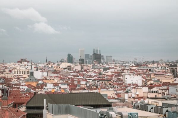 Una vista aérea cautivadora del skyline de Madrid, que muestra la arquitectura urbana y el paisaje de la ciudad bajo un cielo nublado.