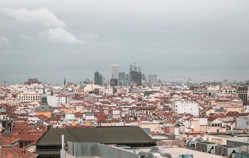 Una vista aérea cautivadora del skyline de Madrid, que muestra la arquitectura urbana y el paisaje de la ciudad bajo un cielo nublado.
