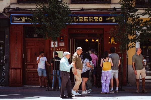 Personas reunidas fuera de la Taberna Alberto en Madrid, España, capturando la vida callejera local.